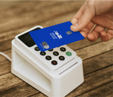 An image of someone holding the Hello Alice credit card over a card reader