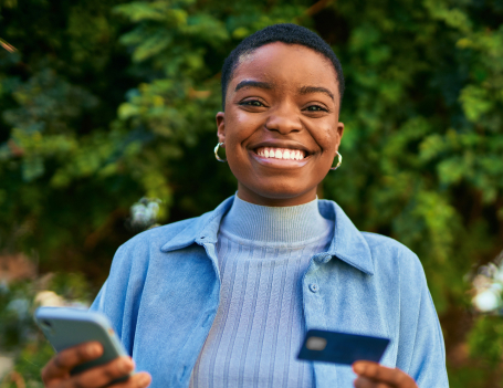 An image of an african-american woman smiling as she holds the Hello Alice credit card