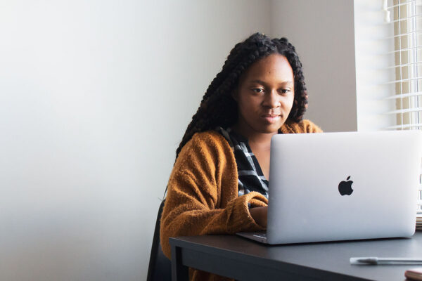 A minority business owner sitting at her desk with a laptop.