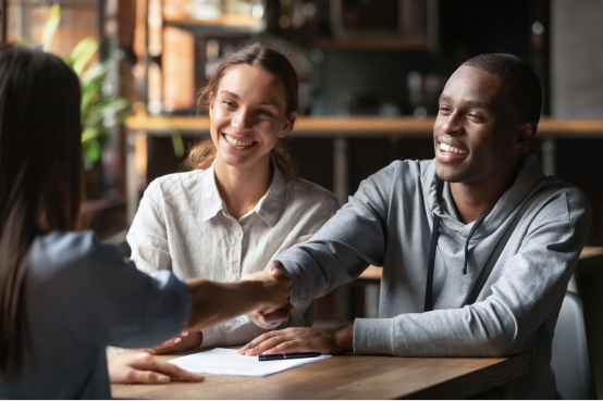 An image of two women and a man shaking hands at a table