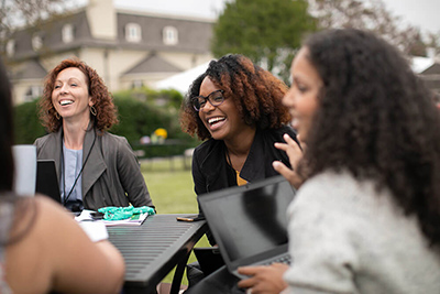 A group of women sitting outside at a table laughing